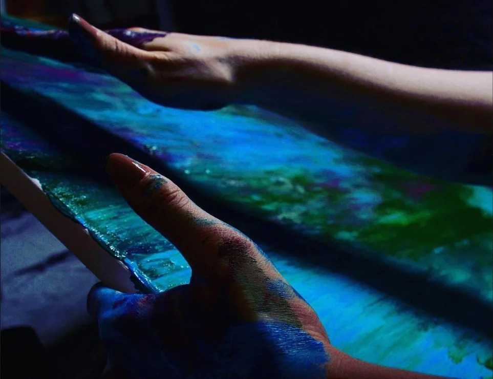 Simona Gür painting directly with her hands, fingers covered in wet paint